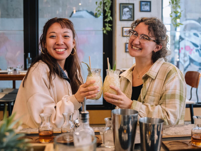 Two smiling women enjoying a cocktail together